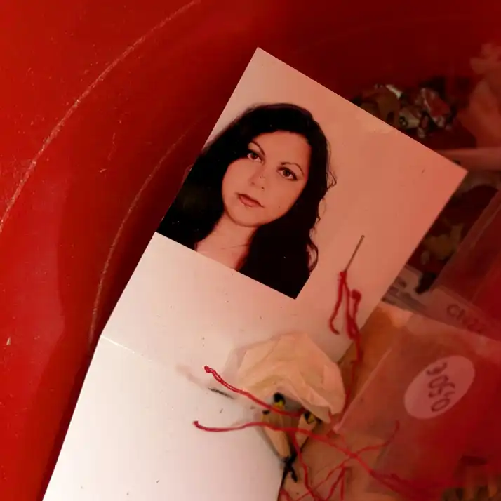 Photo of a female face on white paper in red container.